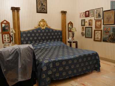 Una porta ci introduce invece nella camera da letto. Qui l'atmosfera si alleggerisce: le pareti sono tappezzate da una carta da parati a righe in colori pastello e spicca il grande letto matrimoniale